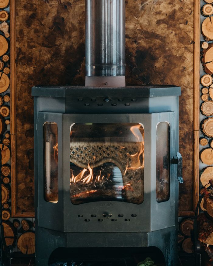 Orange flame of vintage metal burning fireplace placed near wooden wall in cozy house